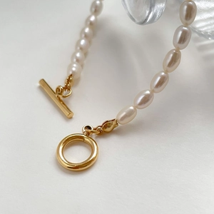 Close-up of gold T-bar clasp and white rice pearls on a handcrafted jewelry piece