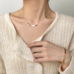 Detail of minimalist geometric cube necklace and matching bracelet set worn by a model