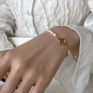 Close-up of elegant freshwater pearl bracelet featuring a glossy gold OT buckle closure