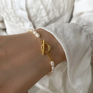 Detail of natural freshwater pearl bracelet with golden toggle clasp on a sleeve