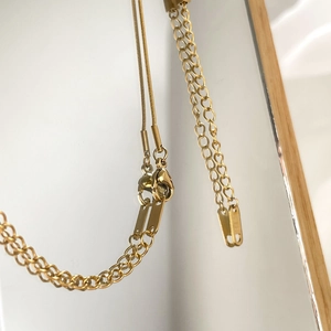 Detailed macro view of gold layered snake chain and lobster clasp with polished metal tag