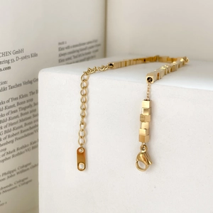 Close-up of golden geometric cube chain bracelet with lobster clasp and extender