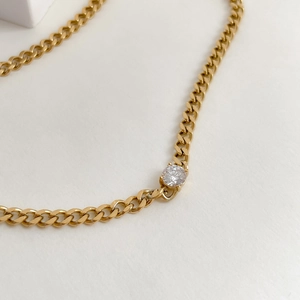 Detailed close-up of a golden Cuban link necklace with a sparkling white round zircon stone