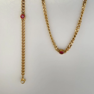 Detail of gold curb chain necklace featuring faceted red zircon stones and lobster clasp