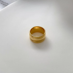 Macro view of wide gold-plated ring with polished curved surface and hollow buckle design