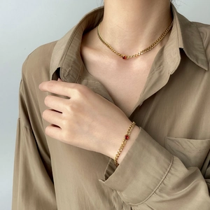 Gold Cuban chain necklace and bracelet set featuring a central deep red gemstone