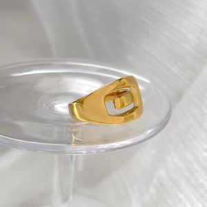 Detailed view of gold geometric hollow ring with mirror finish on glass display stand