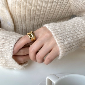 Close-up of a double-layered gold wide ring worn on finger with a minimalist design