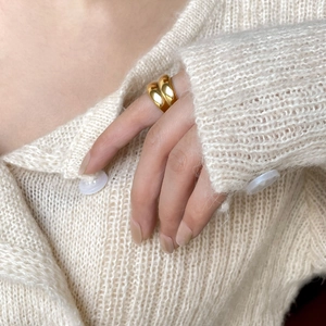 Minimalist double-layered gold curved ring on hand with cream knit sweater background