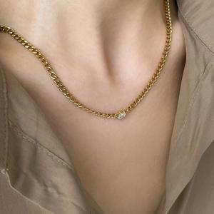 Elegant gold Cuban link necklace with round white zircon pendant worn on a model