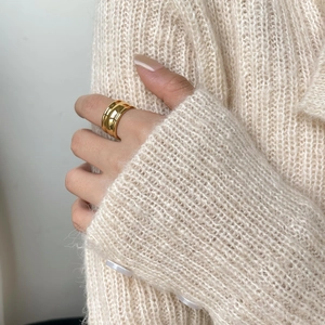 Close-up of a double-layered gold wide ring with irregular design on a knitted sleeve