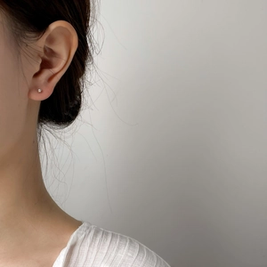 Dettaglio di orecchini a perno minimalisti in oro con zirconi indossati da una modella