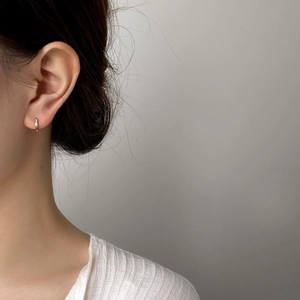 Dettaglio di orecchini a cerchio dorati con piccoli zirconi indossati da una modella