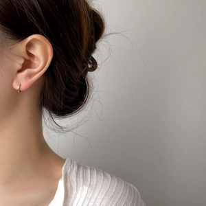 Dettaglio di un orecchino a cerchio dorato con micro-pavé di zirconi bianchi su modella