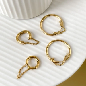 Set of four 18K gold plated stainless steel hoop earrings with tassel chains on white plate