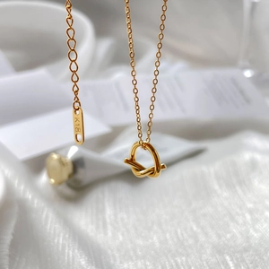 Macro detail of 18K gold knot pendant necklace showing polished finish and K18 hallmark