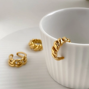 Detailed close-up of gold-plated twisted rope and chain link rings on a white cup rim