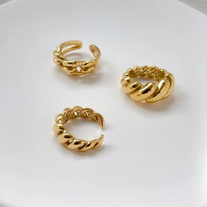 Detailed view of three gold-plated twisted rope rings with high-polish metallic finish