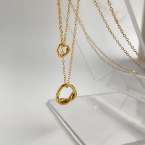 Close-up of gold double knot pendant necklace on a transparent display stand