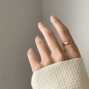 Vue détaillée d'une bague minimaliste en or avec zircons portée sur un pull en maille