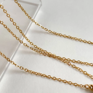 Detailed macro view of golden cable chain links on a transparent jewelry display stand