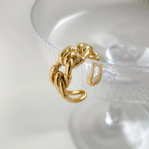 Detail of gold twisted rope ring hanging on glass edge with textured reflections