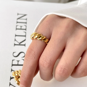 Close-up of a French style twisted gold-plated ring with glossy metallic finish