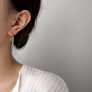 Detail of gold-plated hoop earrings featuring inner tassels and chain accents
