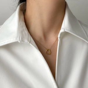 Detailed view of an elegant gold knot pendant necklace on a model with white shirt