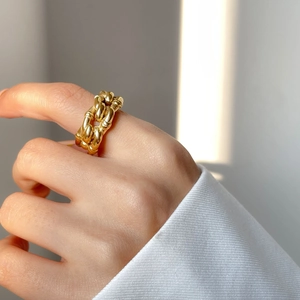 Detailed close-up of a twisted gold-plated rope ring with a metallic mirror finish