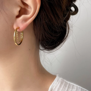 Close-up of polished 18K gold-plated hoop earrings with a fine inner tassel chain