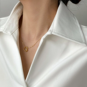 Close-up of gold knotted circle pendant necklace on a white shirt for women