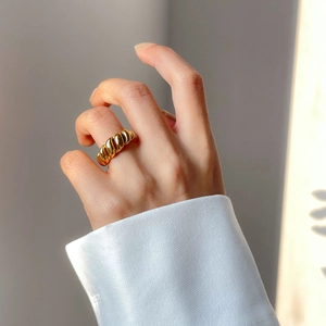 Detail of gold twisted croissant ring with polished finish on model's index finger