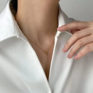 Close-up of minimalist gold knotted necklace worn with a white shirt for a modern look