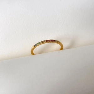 Macro d'une bague en or 18 carats avec zircons arc-en-ciel sur fond de papier blanc