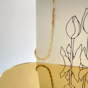 Detail of twisted multi-strand gold snake bone chain with lobster clasp on beige card
