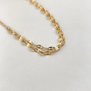 Macro shot of double-layered gold flat oval link snake chain necklace in titanium steel
