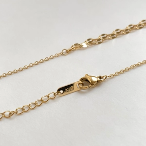 Macro detail of 18K gold snake chain featuring a lobster clasp and K18 hallmark tag