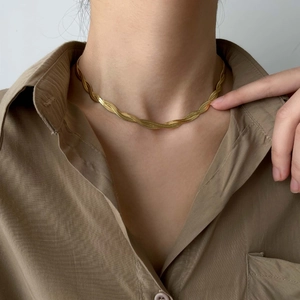 Close-up of a golden twisted snake chain necklace on a model wearing a khaki shirt