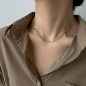 Close-up of golden lip-shaped chain necklace on model neck with detailed metal texture