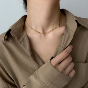 Detailed view of a gold snake chain necklace with a elegant texture on a model's neck