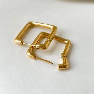 Vue détaillée de boucles d'oreilles créoles carrées dorées avec finition miroir