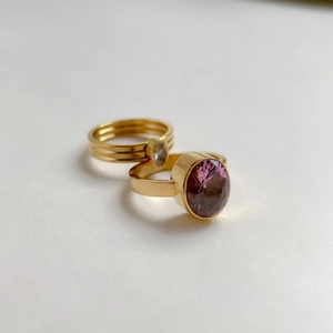 Détail macro de bagues dorées avec zircon violet ovale et anneau triple épaisseur