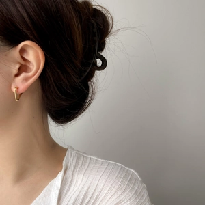 Gros plan d'élégantes boucles d'oreilles triangle dorées portées par un mannequin en douceur