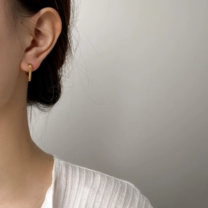 Boucles d'oreilles géométriques en U dorées polies portées avec un style minimaliste