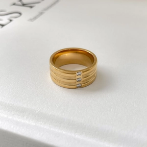 Détail d'une bague large plaquée or 18 carats avec trois oxydes de zirconium verticaux