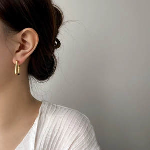 Gros plan sur des boucles d'oreilles rectangulaires dorées pour un look géométrique