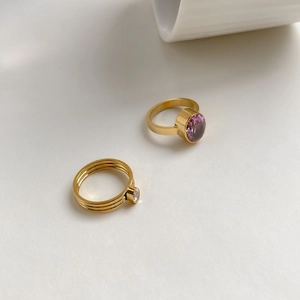 Vue de dessus de bagues dorées avec zircon violet ovale et anneau triple à pierre claire