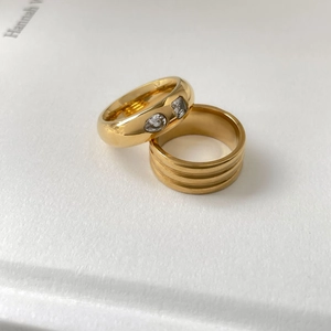 Détail de bagues superposables dorées avec trois zircons incrustés et anneau à rainures