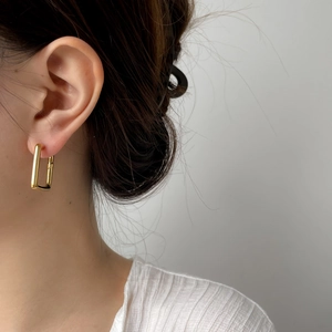 Vue détaillée de boucles d'oreilles rectangulaires dorées portées par un mannequin